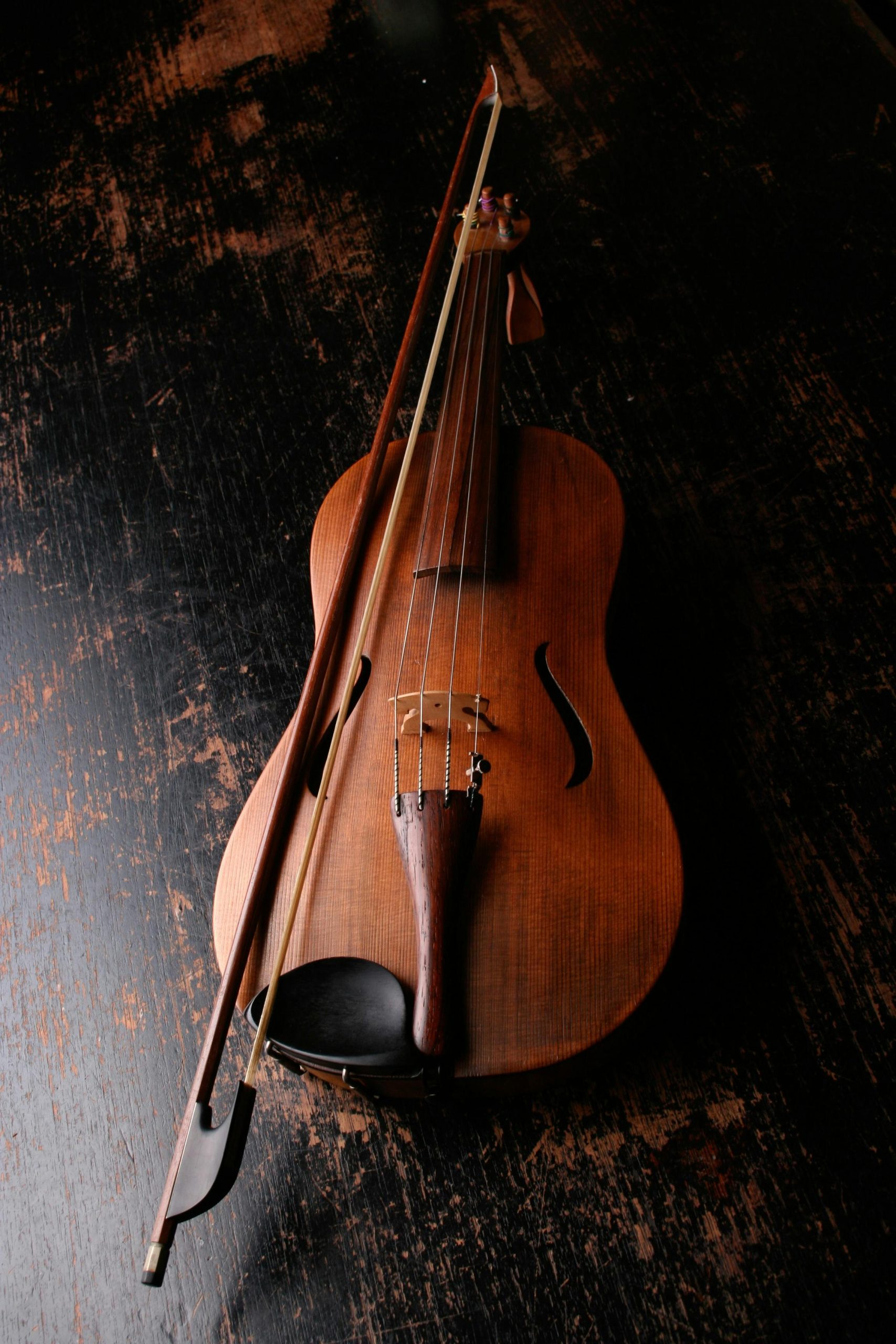 A beautifully crafted violin rests on a dark wooden surface, evoking a classic and artistic mood. Music matters. Hearing music is feeling music.